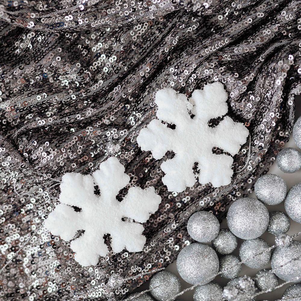 White snowflake ornament on silver sequin background