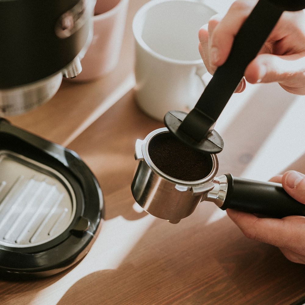 Barista pressing ground coffee in a coffee machine filter