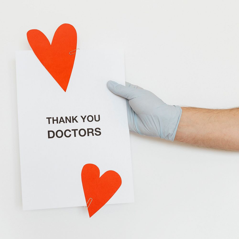Gloved hand holding a thank you doctors card 