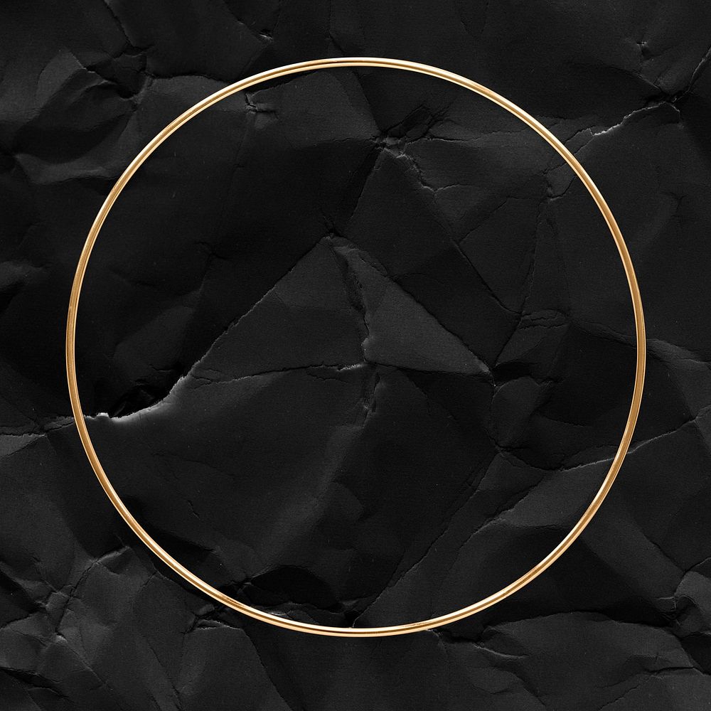 Round gold frame on a crumpled black paper textured background