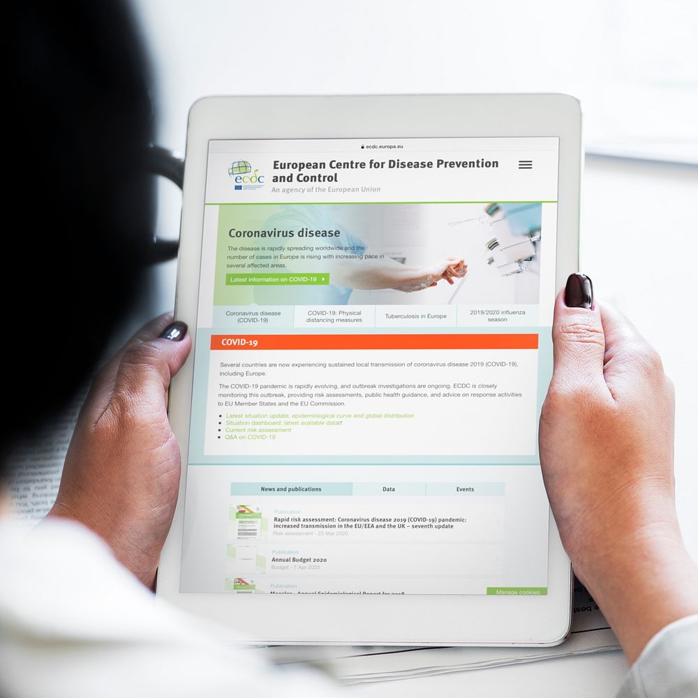 Woman reading coronavirus information from a tablet mockup with editorial graphic from  https://www.ecdc.europa.eu/en…