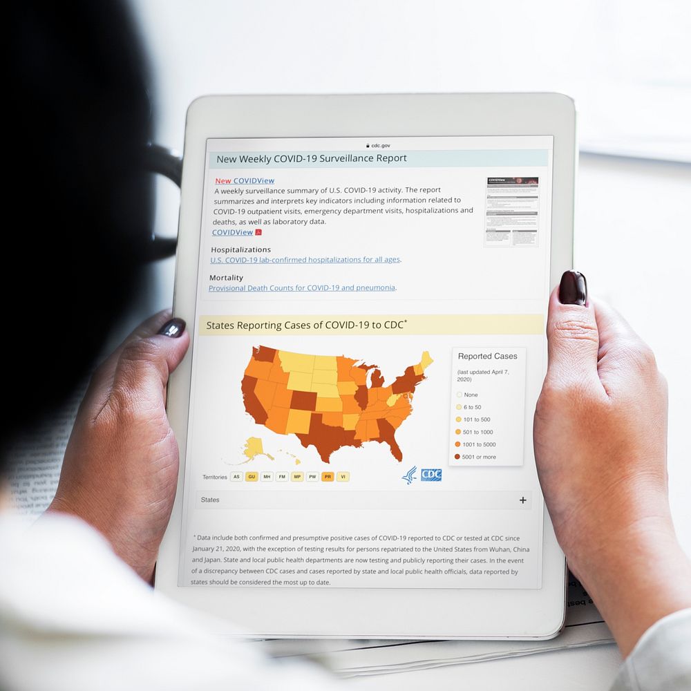 Woman reading coronavirus updates from a tablet mockup with editorial graphic from https://www.cdc.gov/coronavirus/2019…
