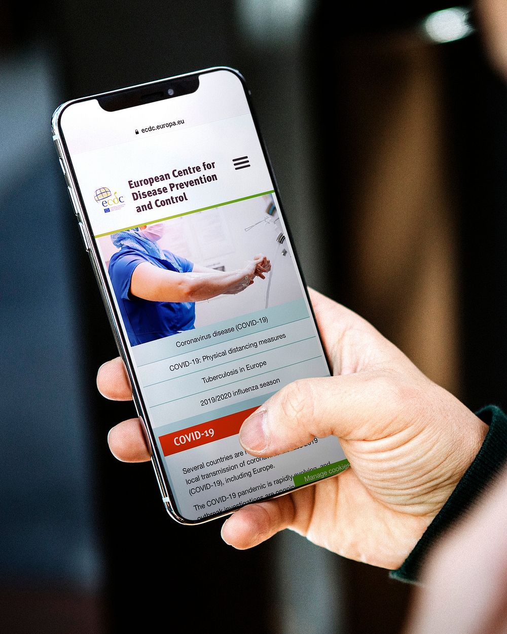 Man reading coronavirus information from a phone mockup with editorial graphic from https://www.ecdc.europa.eu/en accessed…