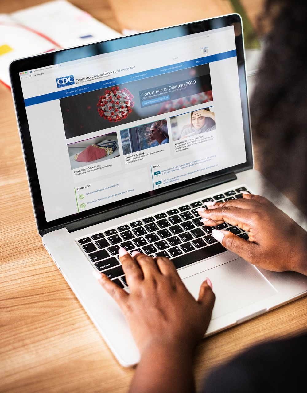 Woman reading coronavirus updates from a laptop mockup with editorial graphic from https://www.cdc.gov accessed on April 8th…