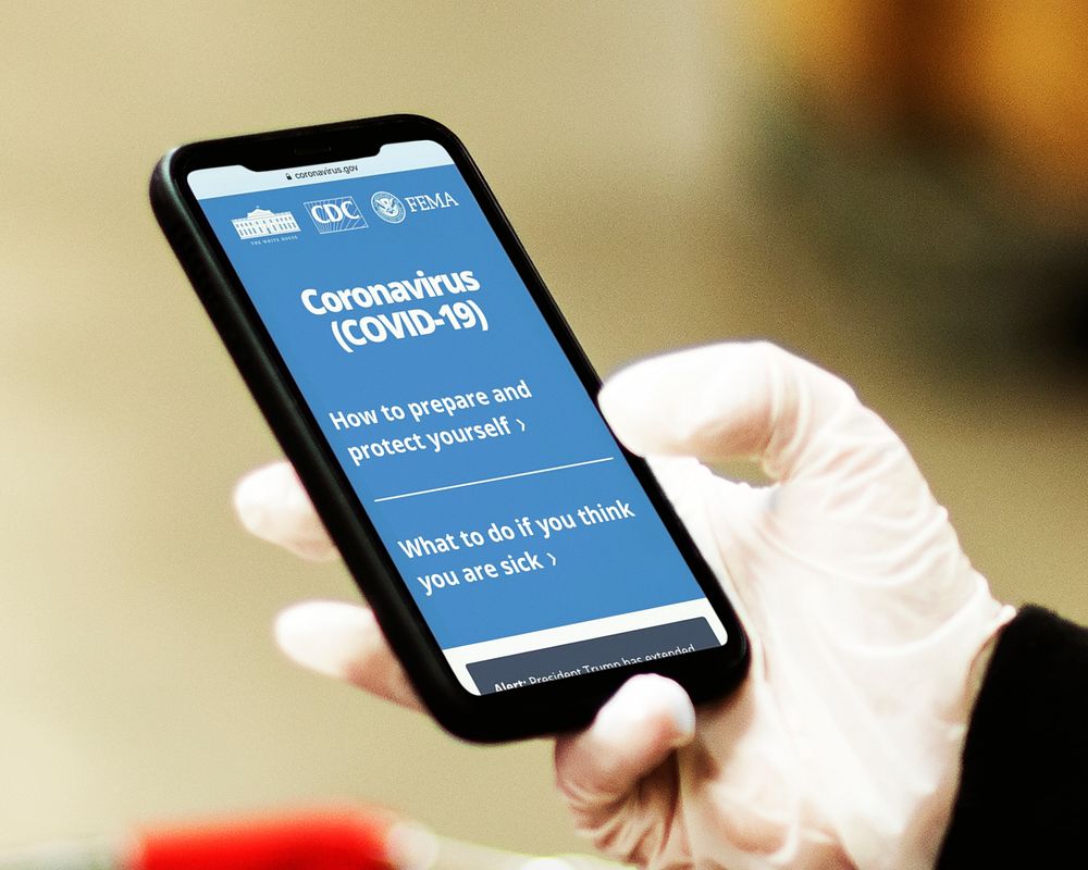Woman reading coronavirus information from a phone mockup with editorial graphic from https://www.coronavirus.gov/ accessed…