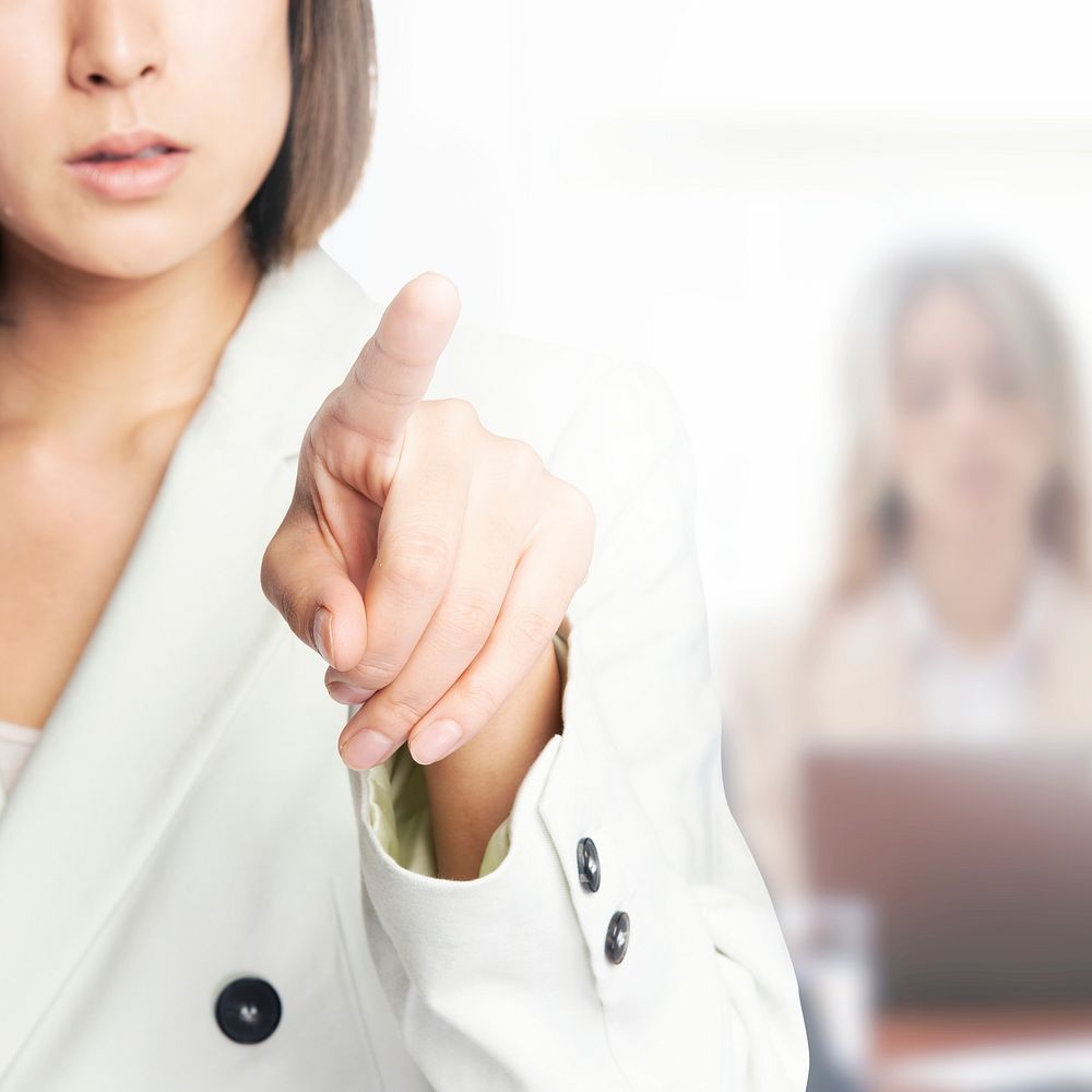 Young businesswoman pointing on invisible screen with team background