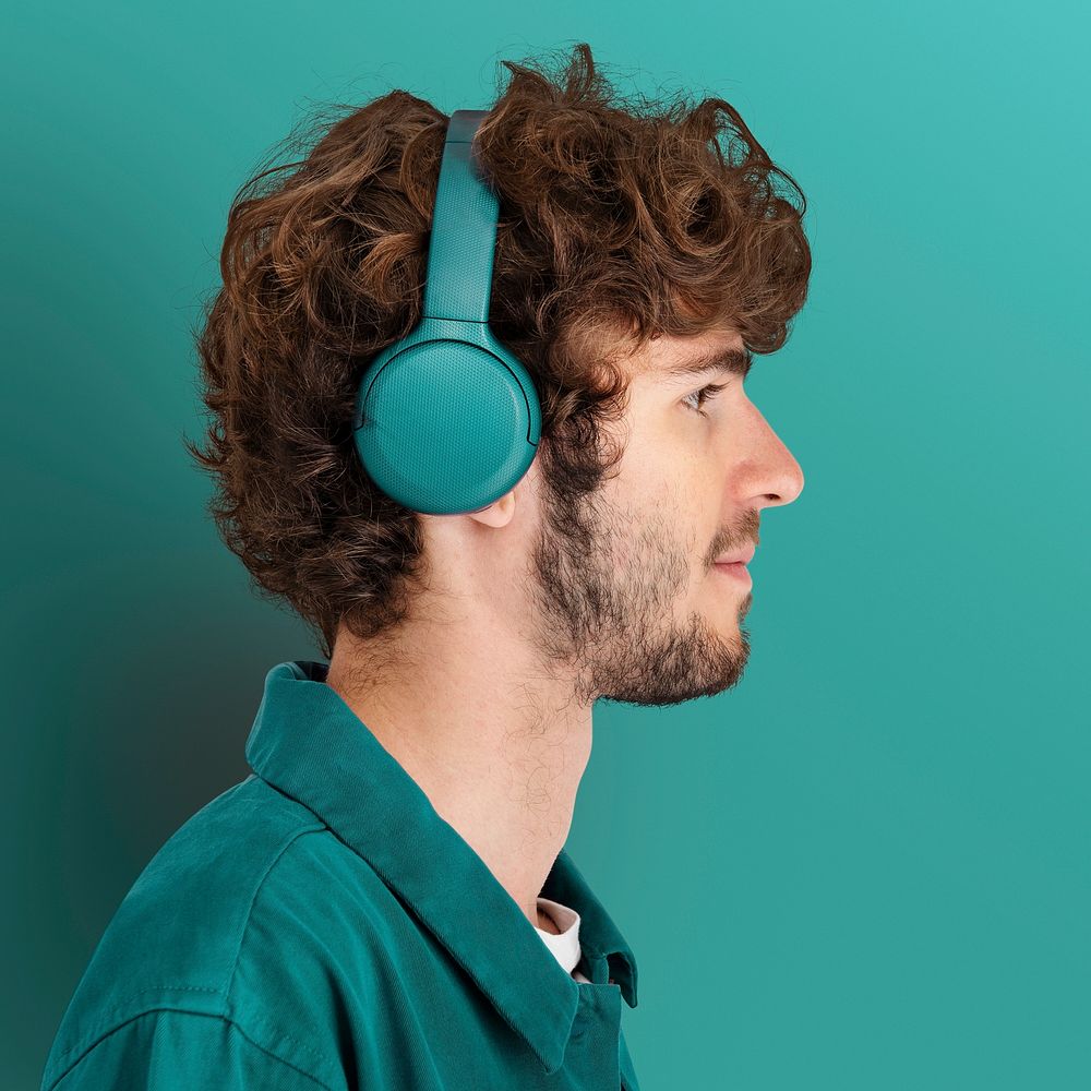 Man wearing headphones standing by the teal green wall
