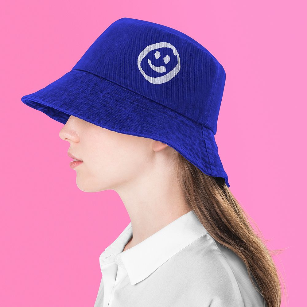 Teenage girl in blue & smiling icon bucket hat for street fashion shoot