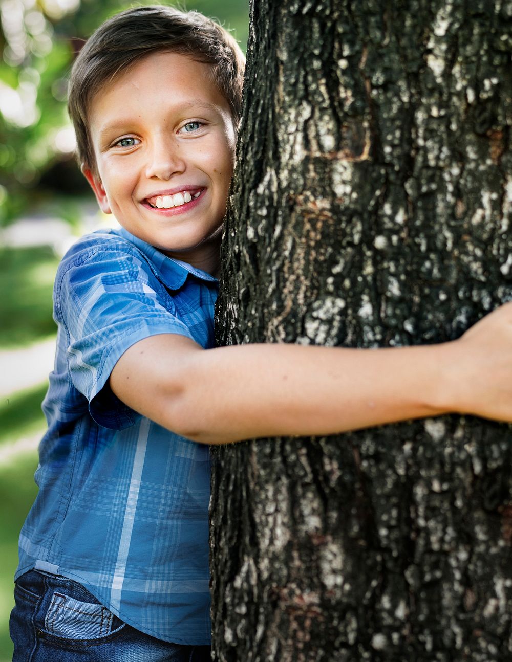 Cheerful boy hugging tree to save environment