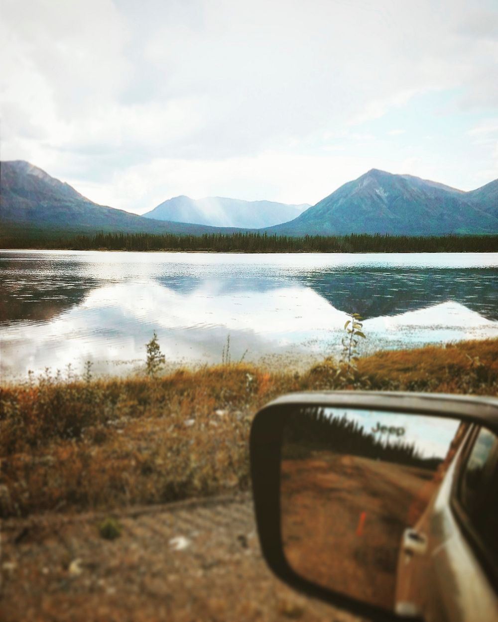 View from a car on its mirror and a quiet lake in the mountains. Original public domain image from Wikimedia Commons
