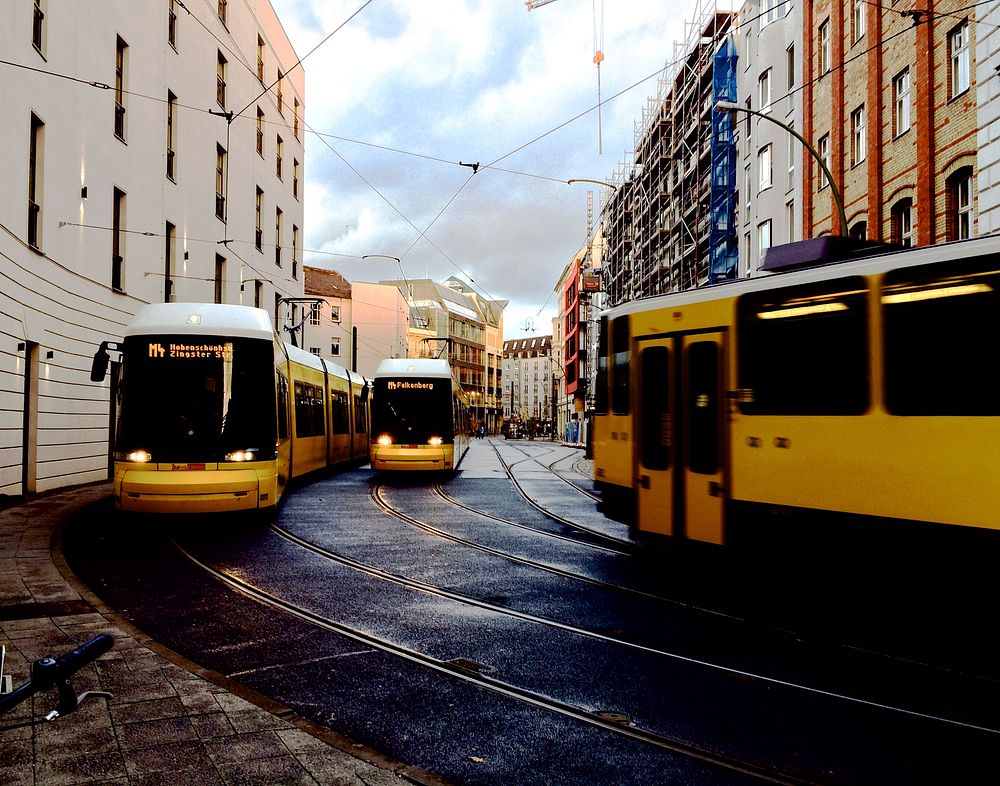 Yellow streetcars around the corner of a city street. Original public domain image from Wikimedia Commons