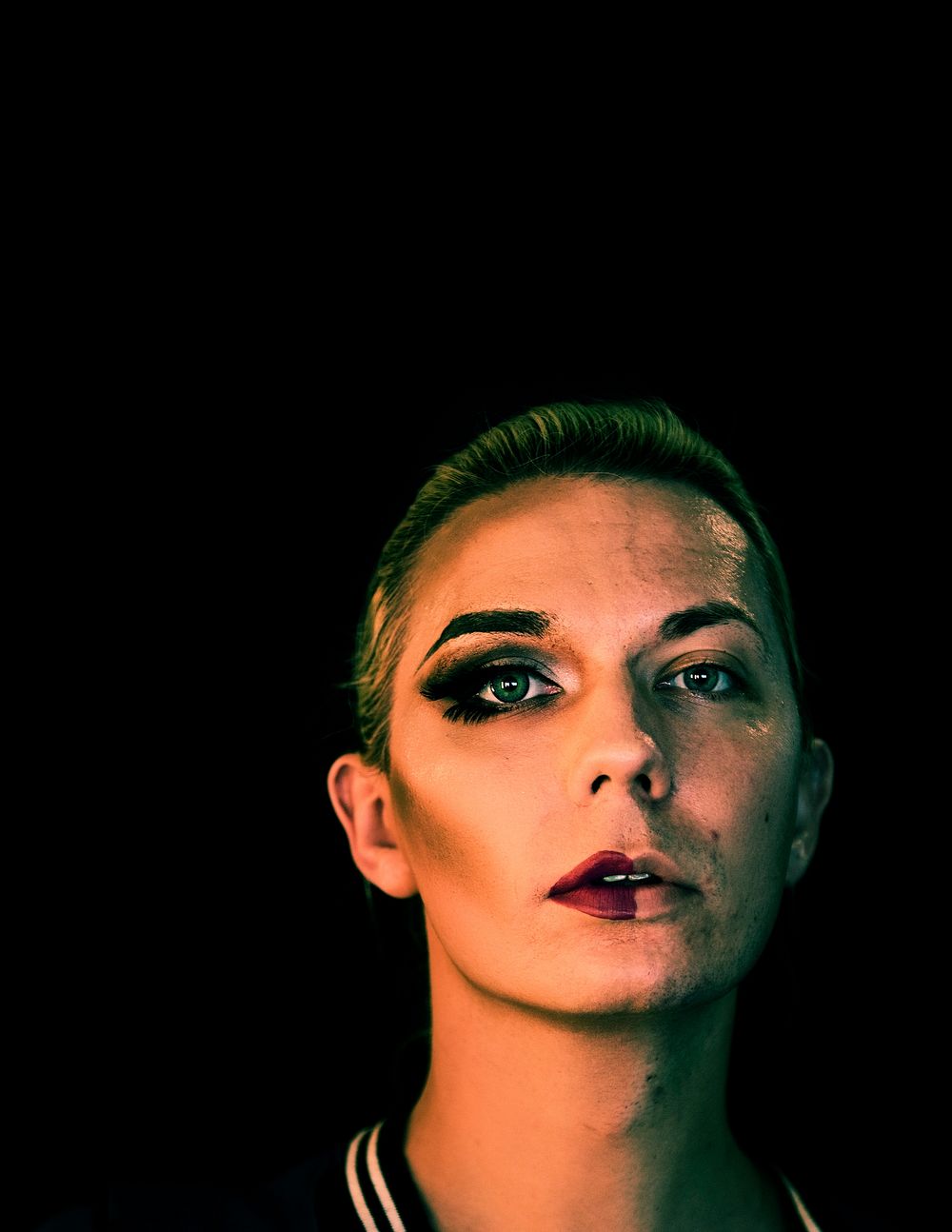 Portrait of a transgender woman with half a makeup on the face