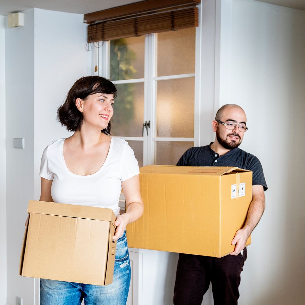 Happy couple moving in together and carrying boxes