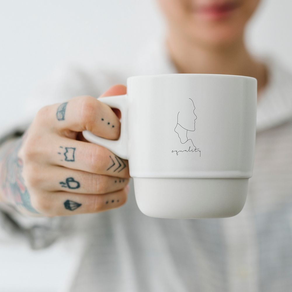 Tattooed woman holding a white coffee cup