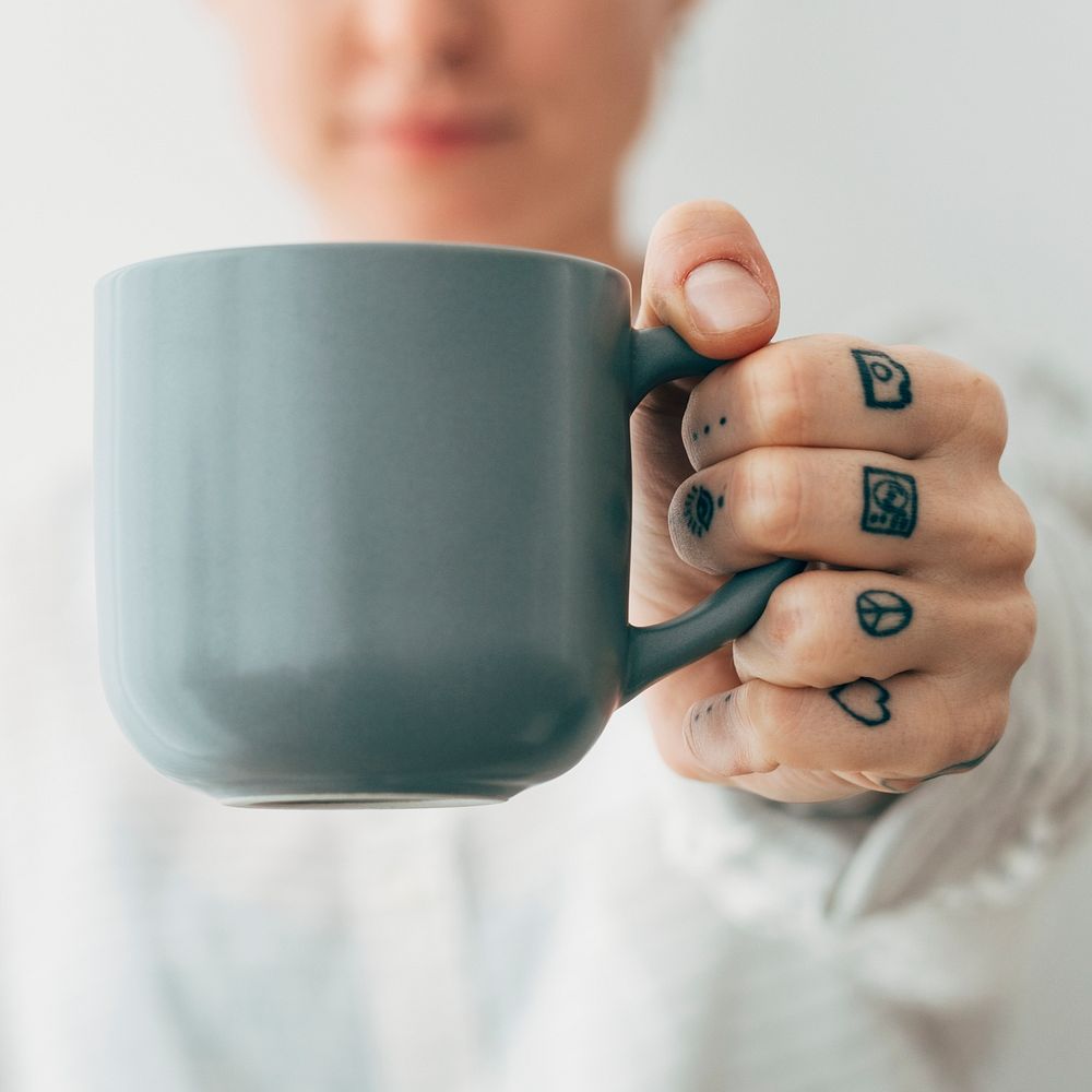 Smiling tattooed woman having a cup coffee