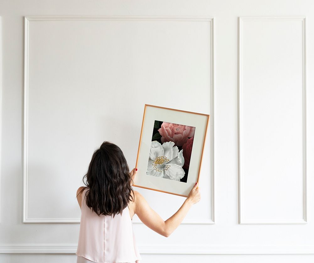 Curator hanging floral art frame on the wall