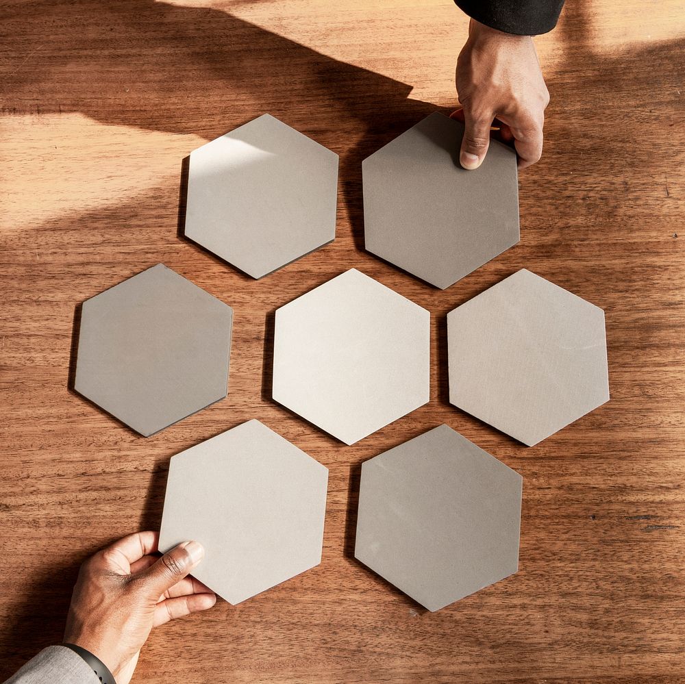 Hands arranging connected hexagon cut out papers