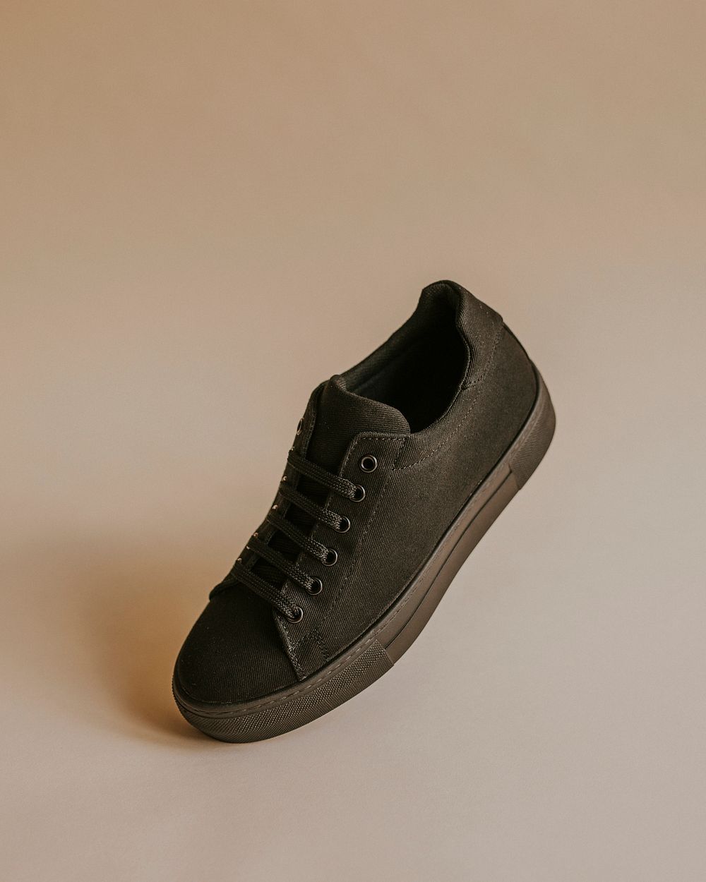 Black canvas sneaker shoe on beige