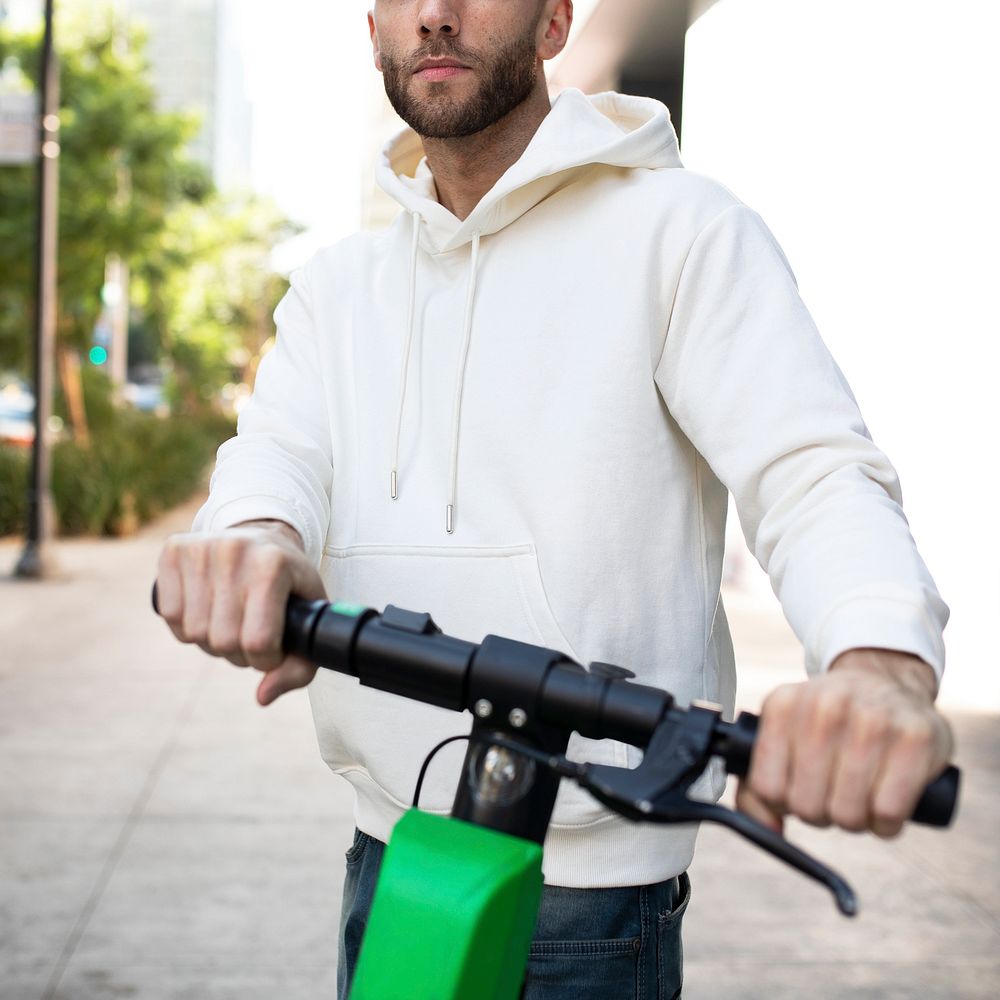 Man with hoodie rining an electric scooter
