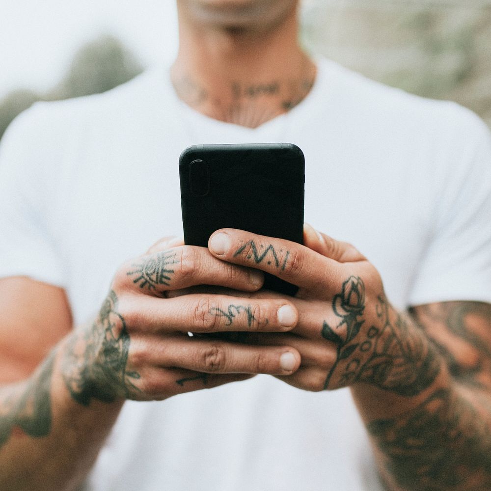 Man with tattooed hands holding a phone. 2 OCTOBER 2020 - CHIPPENHAM, UK