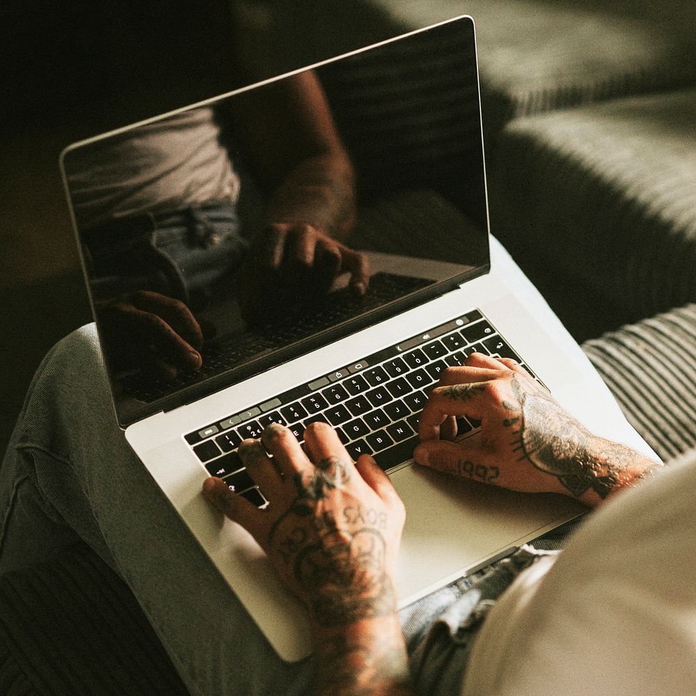 Tattooed alternative man using a laptop