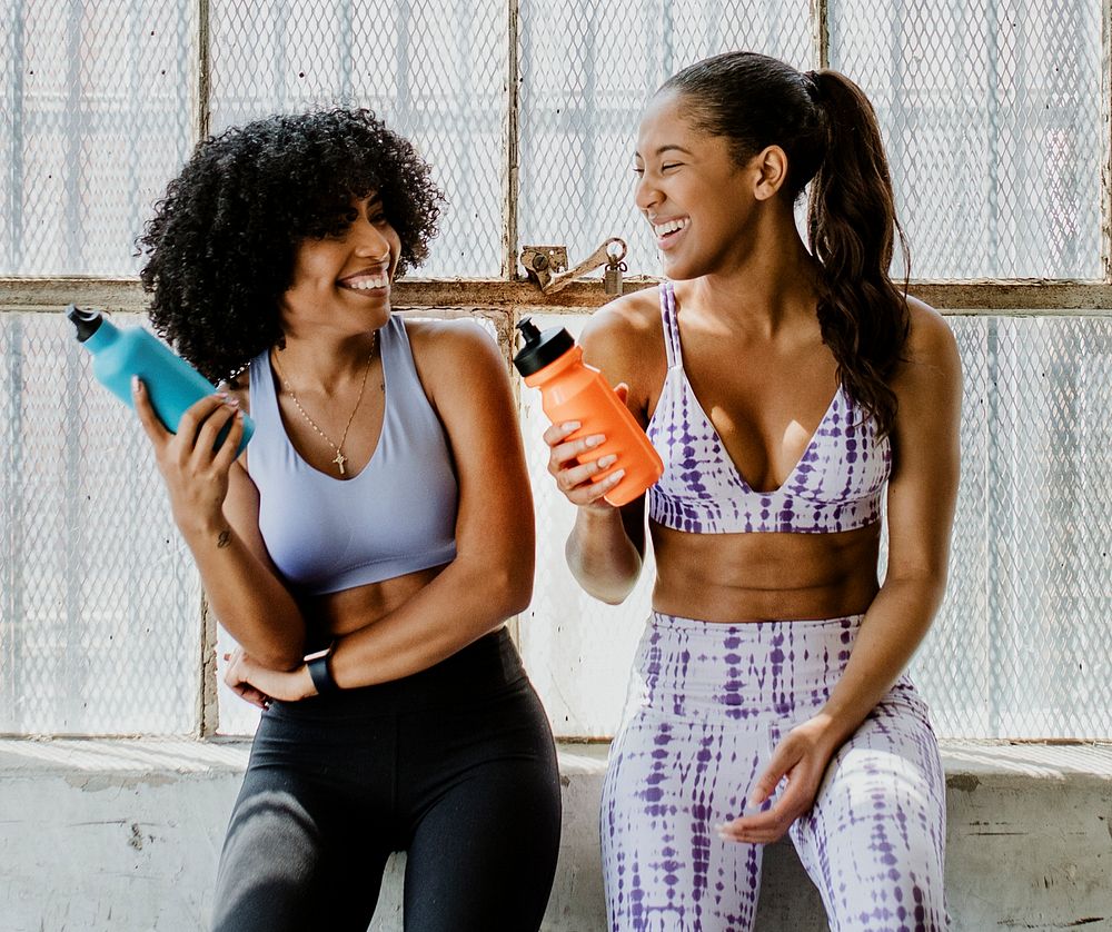 Sportive women talking in a gym while drinking water