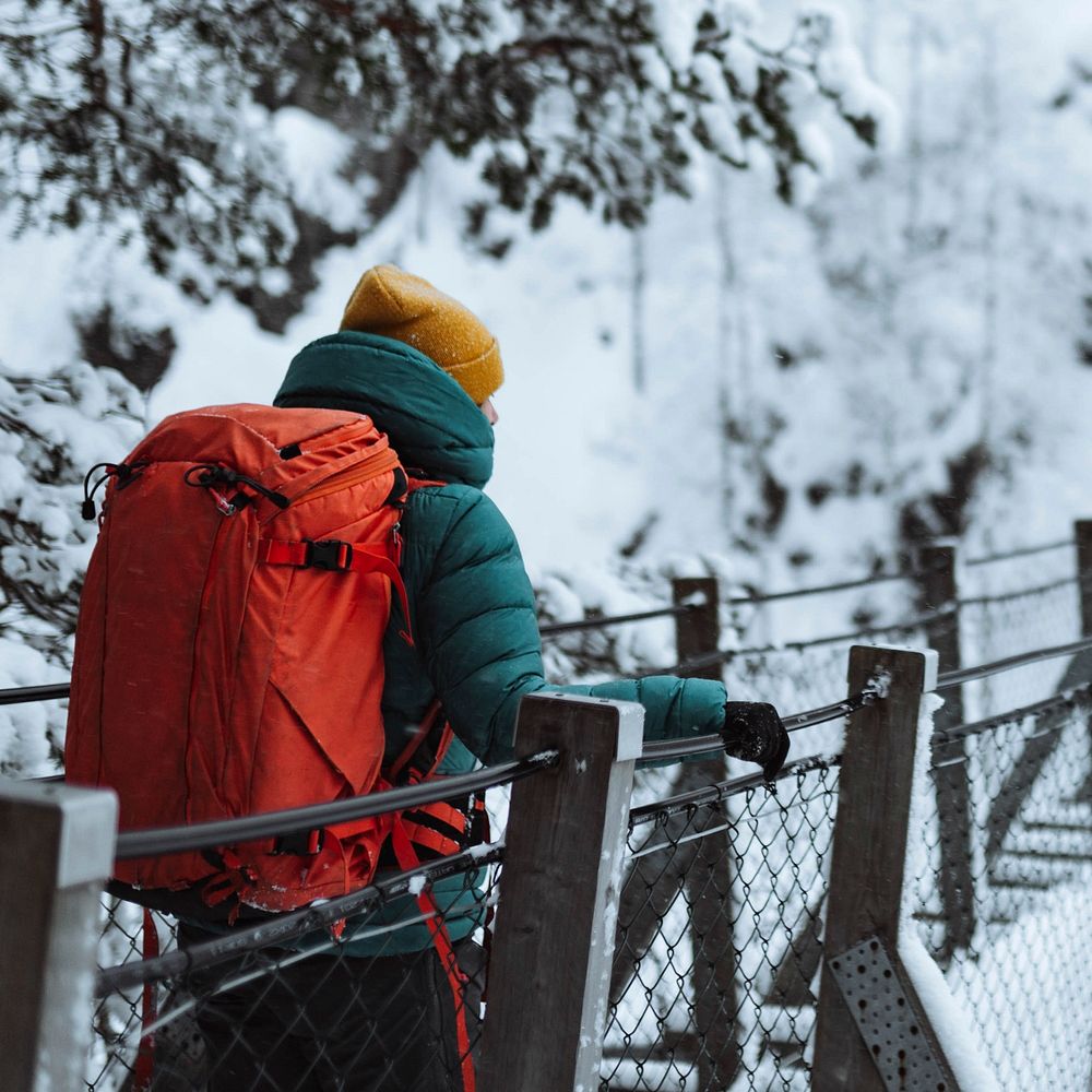 Woman crossing a suspension bridge in a snowy forest, Finland