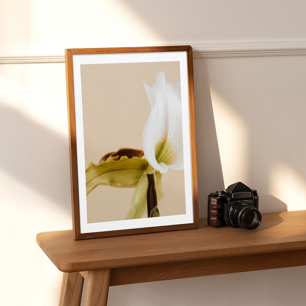 Flower photo frame on wooden table with analog camera