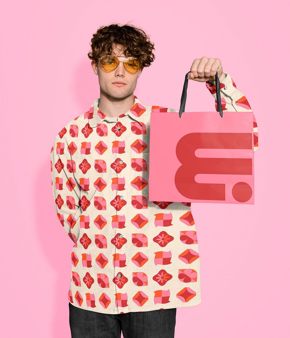 Man wearing pink pattern shirt, holding shopping bag