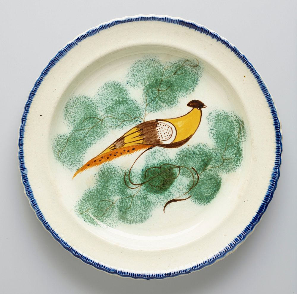 Plate, ceramic-porcelain, decorated with yellow bird in center, narrow blue band around edge; previously catalogued as one…