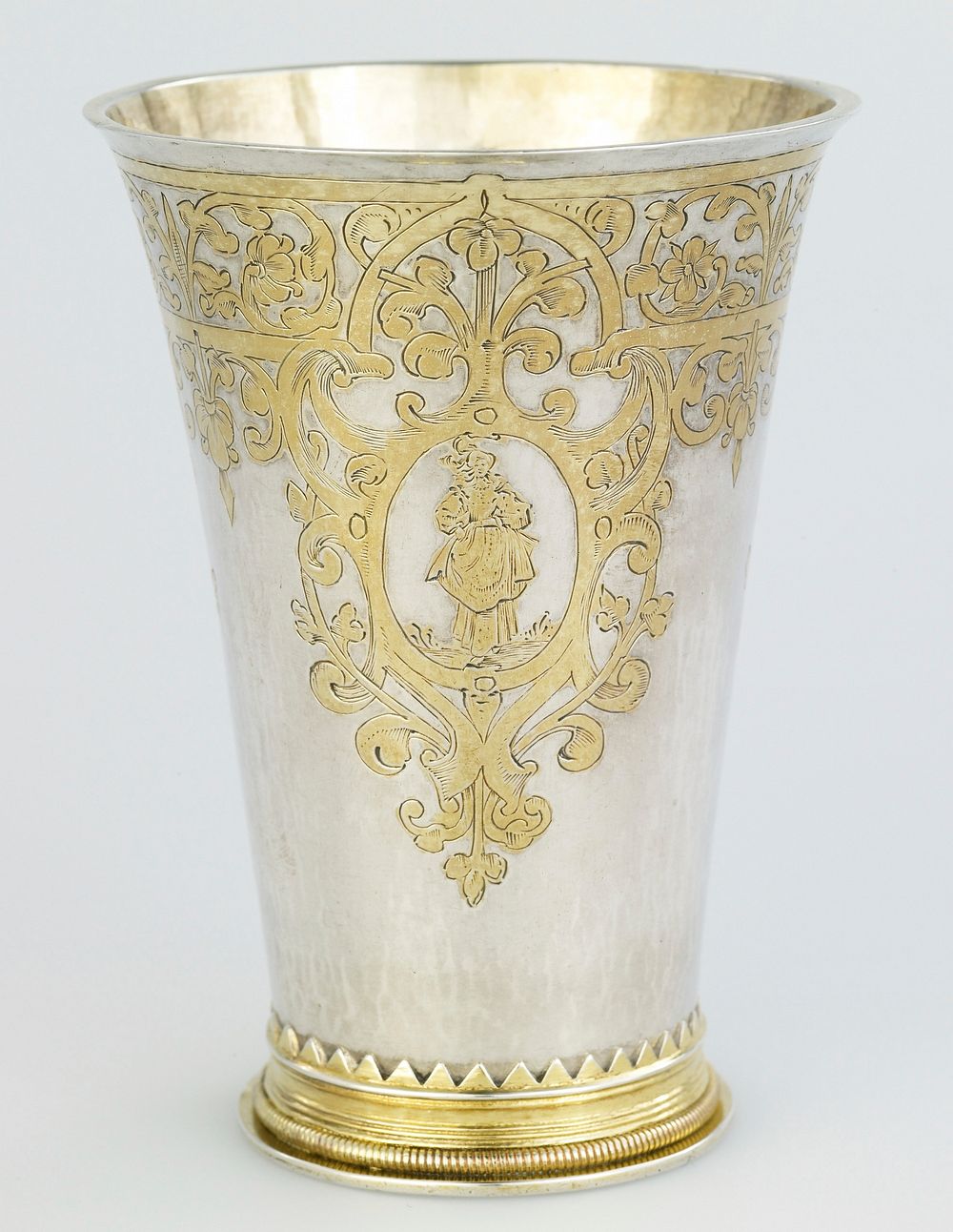 parcel gilt beaker of tapered cylindrical form, engraved with foliate strapwork, enclosing three cartouches of male and…
