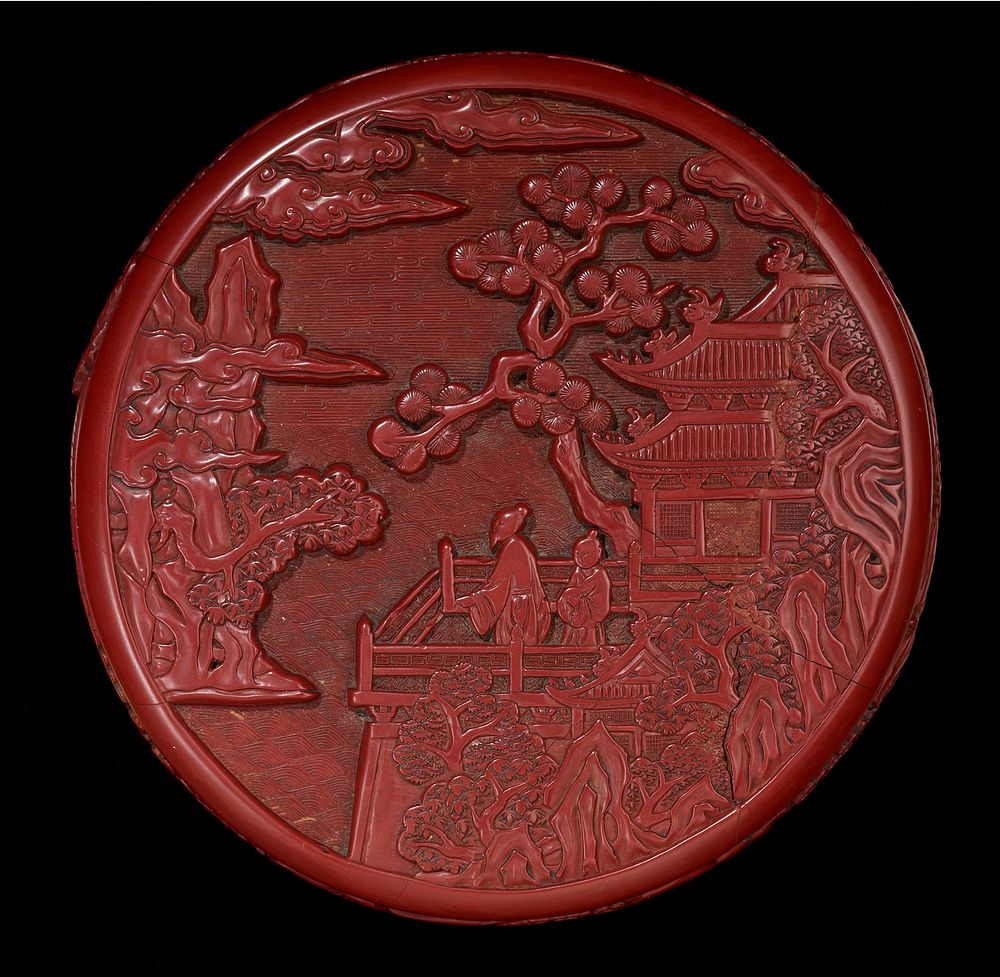 Red with brown interior and bottom; carved with leaf and flower design around edges of box and cover; two figures on a…