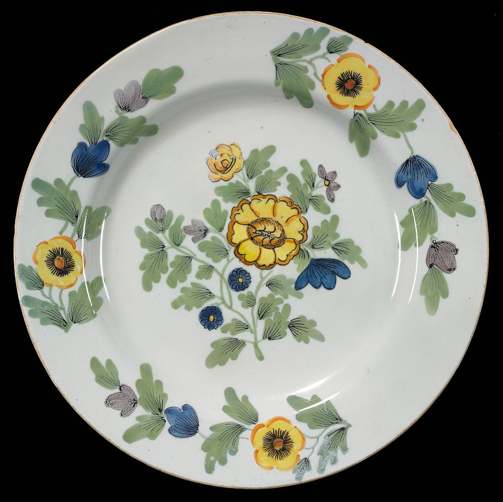 defined rim; foot ring; decorated with central floral spray with yellow, purple and blue flowers; three vining floral sprays…