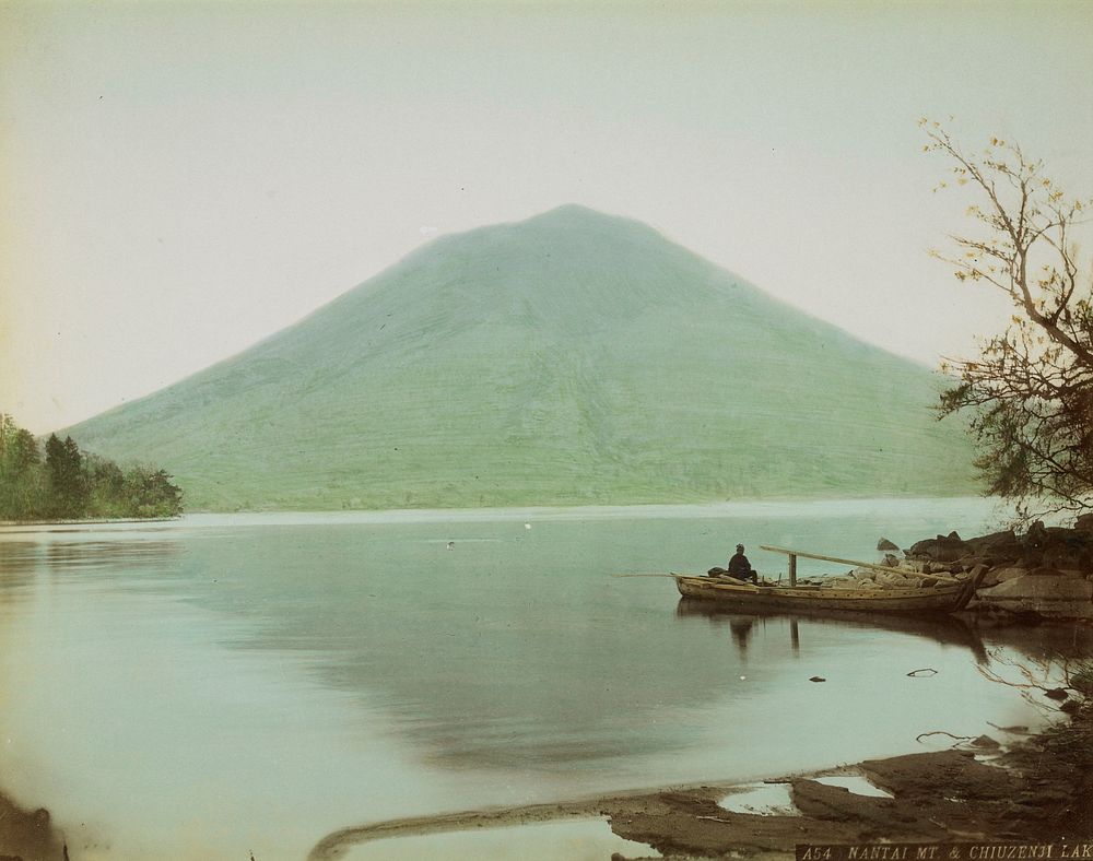 figure in a boat at right on the rocky shore of a calm lake; green mountain in background. Original from the Minneapolis…