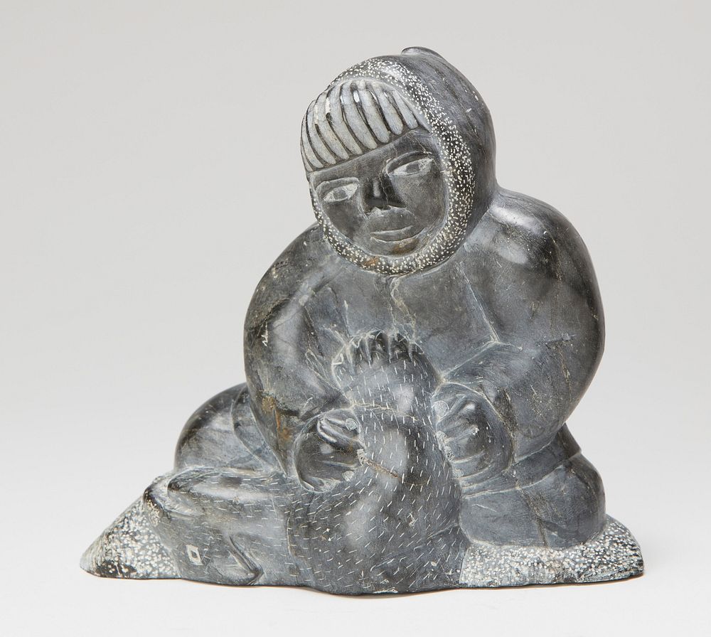 seated figure wearing a hooded parka, with thick, straight bangs, holding a slain animal; carved in grey stone. Original…