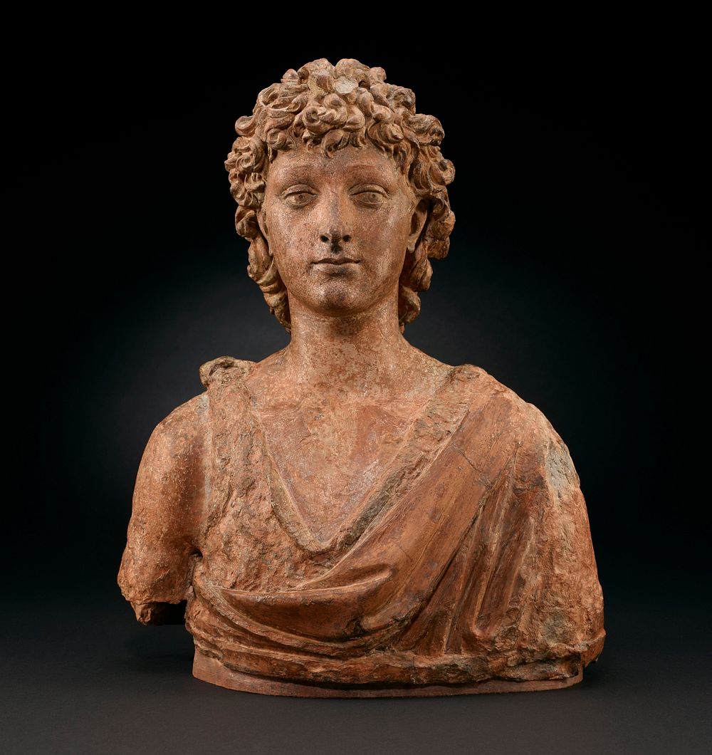 bust of young man with medium-length curly hair; man wears draping garment with low neckline with knot on PR shoulder; bare…