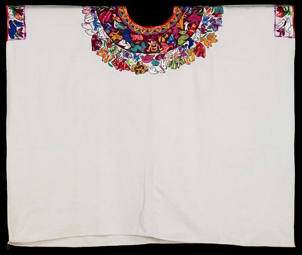 One-panel huipil of white cotton commercial fabric; round-cut neck opening; hand-sewn hem at lower edge. Yellow, rayed sun…