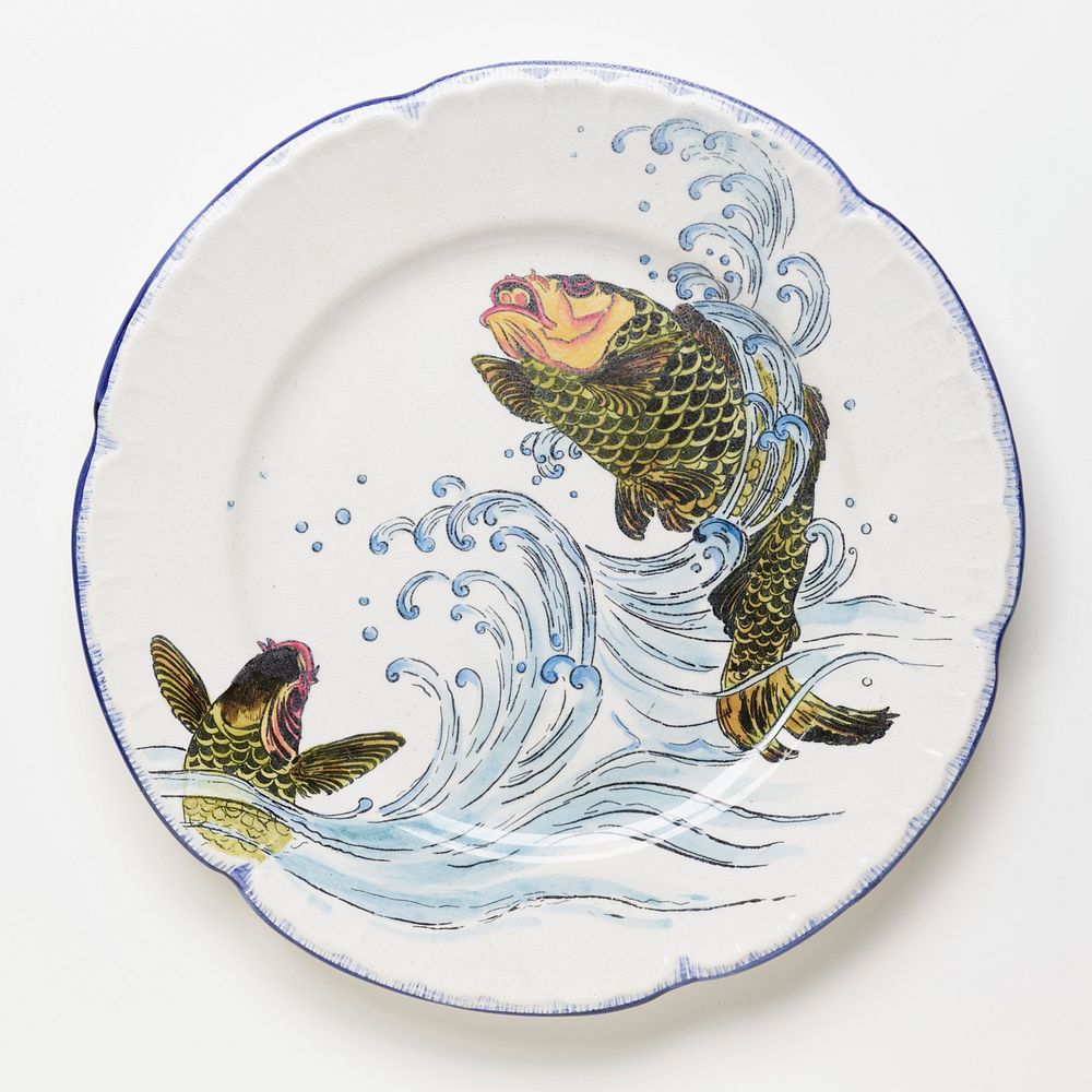 small dinner plate decorated with two jumping green fish with orange heads; blue scalloped edge. Original from the…