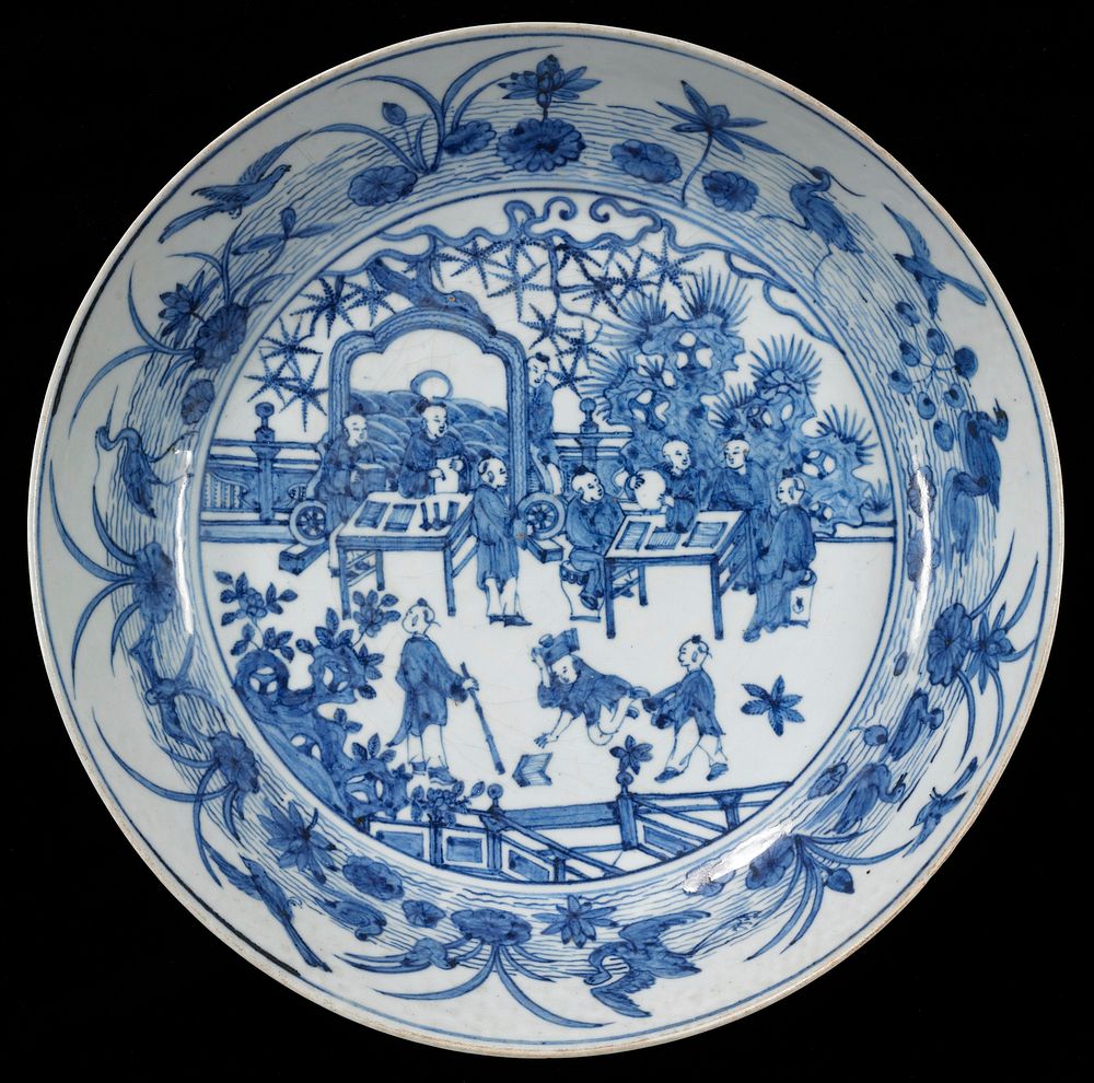 blue and white porcelain; 11 figures seated at 2 tables and standing and kneeling in front; rock in background at R; inner…