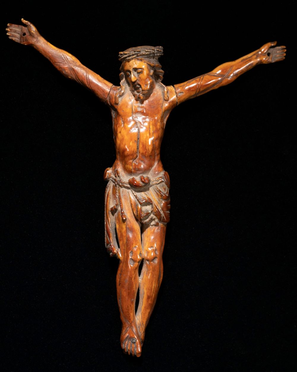 crucified Christ figure wearing crown of thorns, with head tilted slightly to PR and arms outstretched; medium brown.…