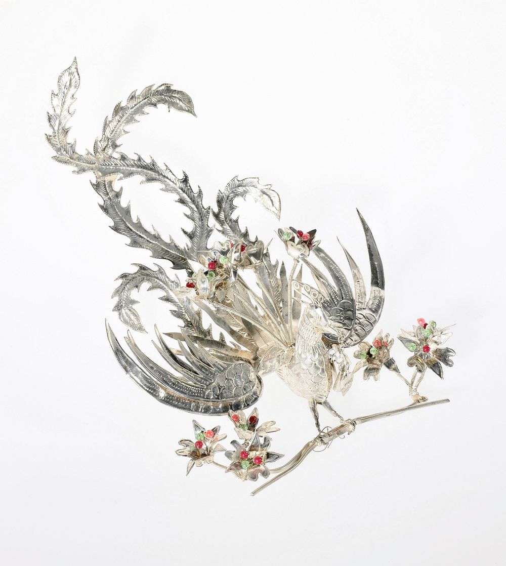 Phoenix standing on hair comb with wings spread and three groups of flowers around it, one to either side and one above…