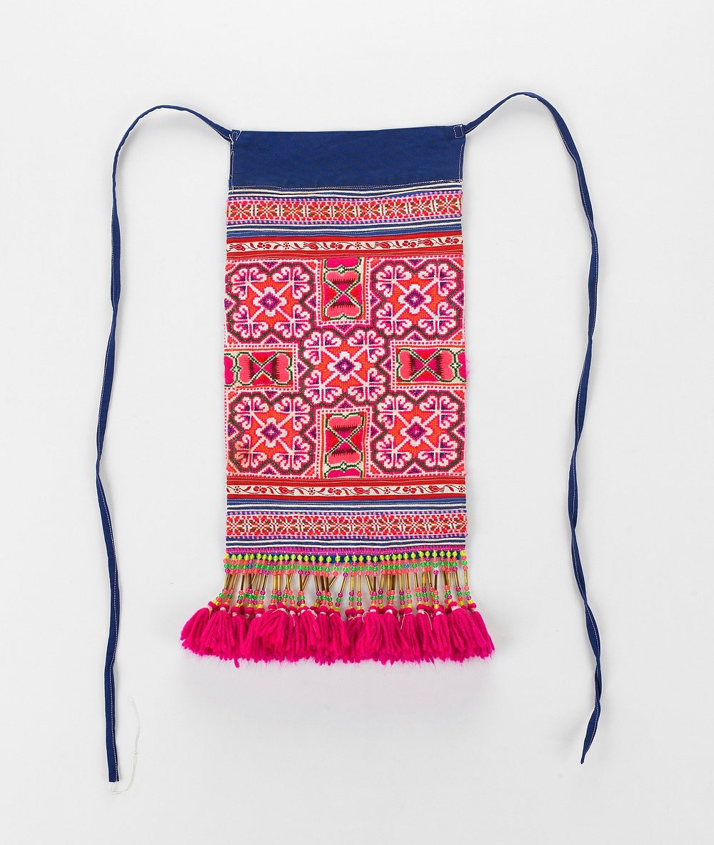 apron with fuchsia tassels attach by yellow, pink and green beads; blue ties and blue band at top; main body embroidered in…