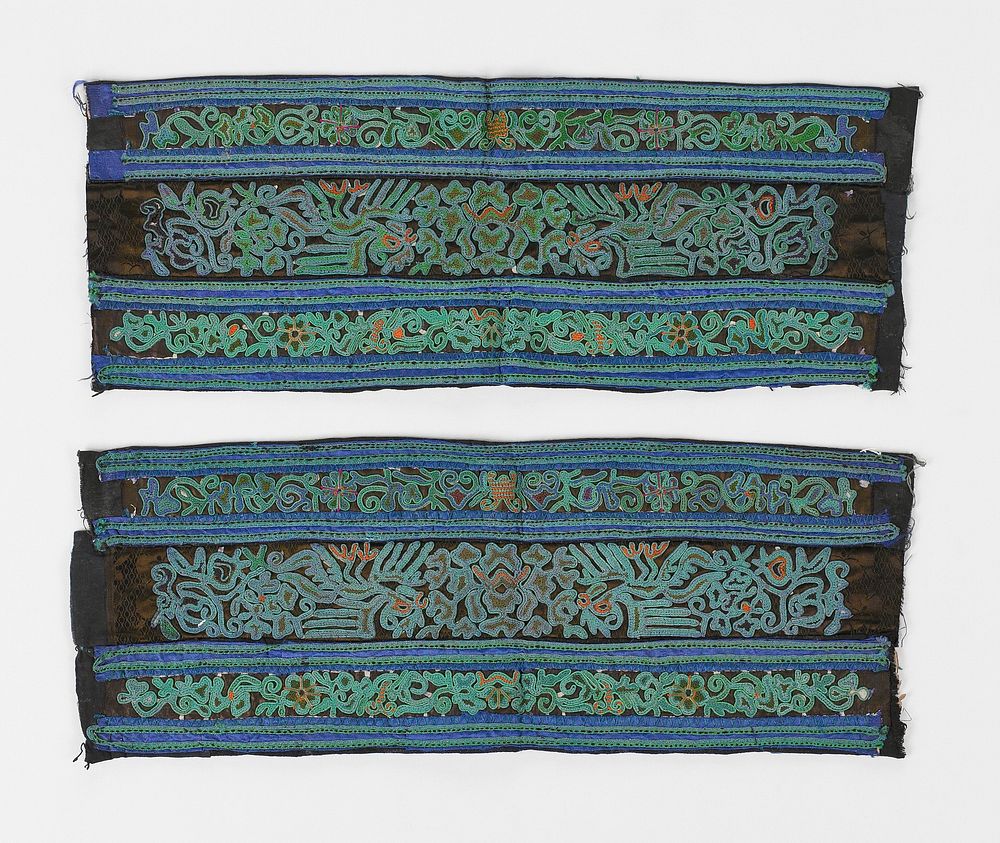 black silk field with four bands of smaller green and blue bands alternating; in between the bands are curvilinear designs…