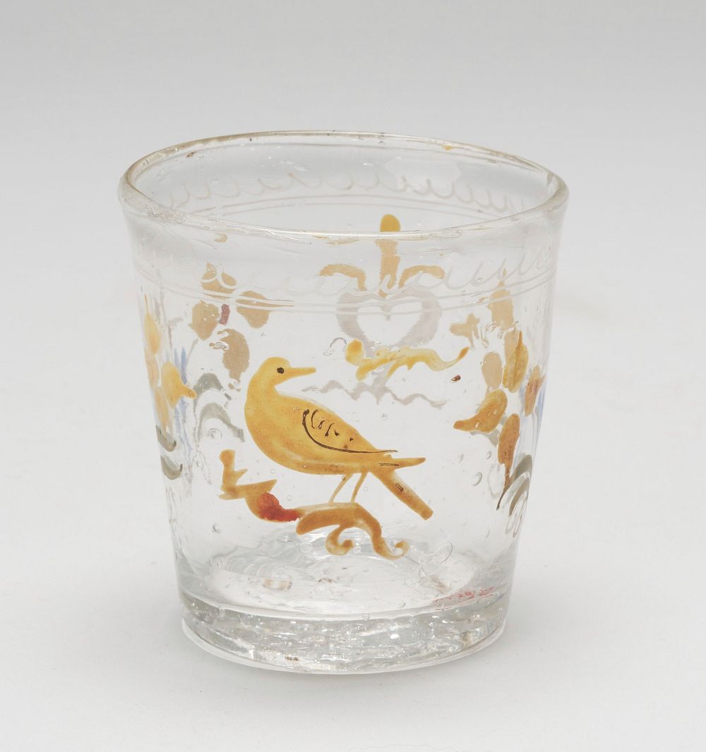 small beaker, clear glass painted in enamel with yellow bird on a branch, a white heart and two floral sprays; Holiday…