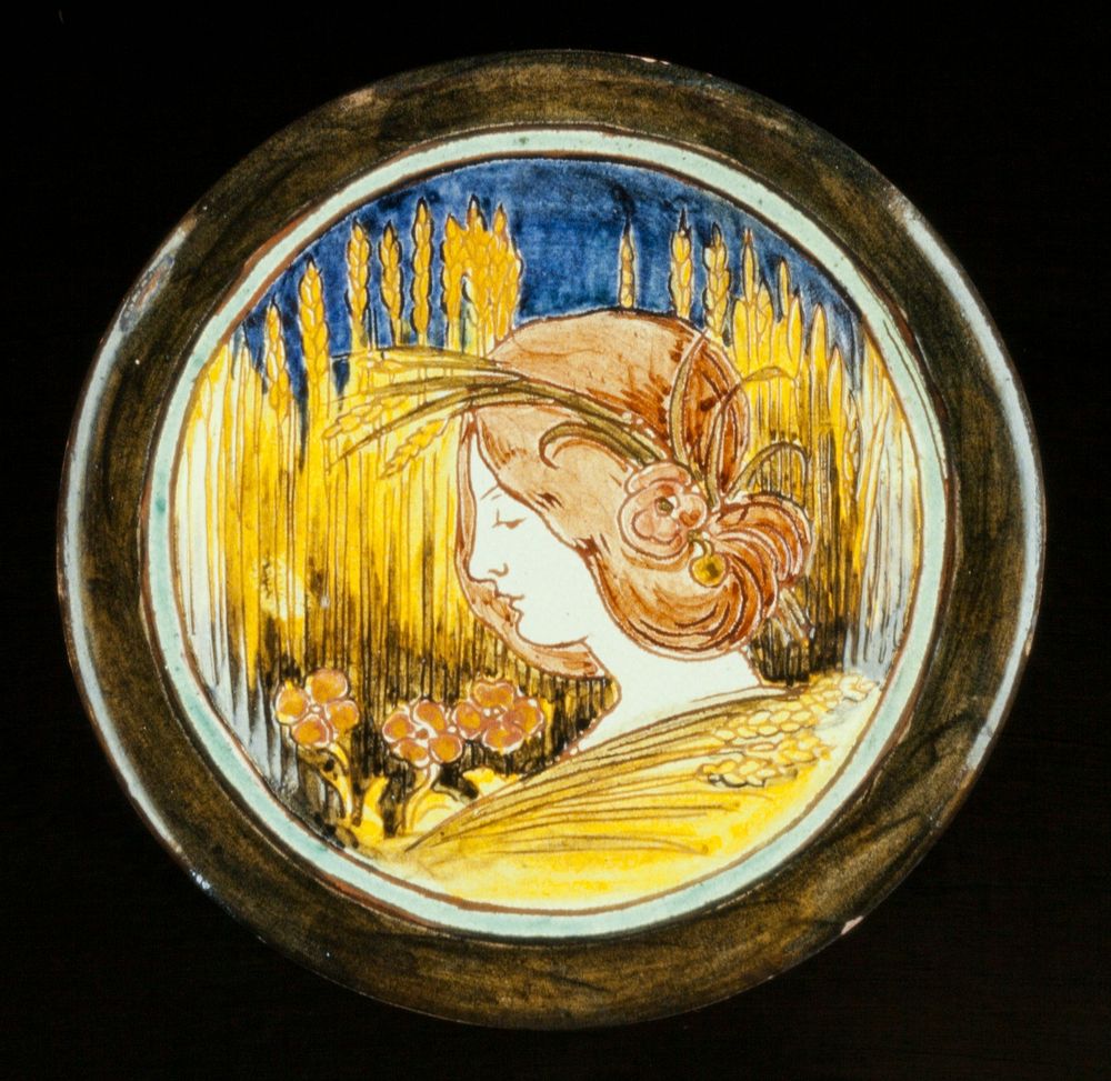 Della Robbia Dish, ceramic, design shows woman's head with garland of wheat, this super-imposed on a wheat-field backgorund…