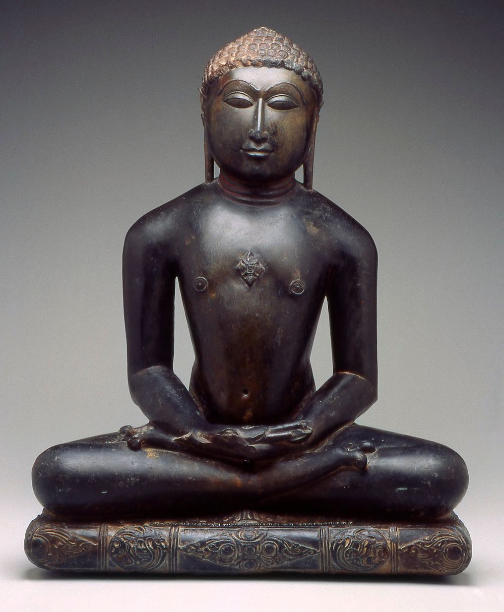 figure seated in dhyanasana with hands in lap; cushion below figure carved with foliate sprays and central quatrefoil…