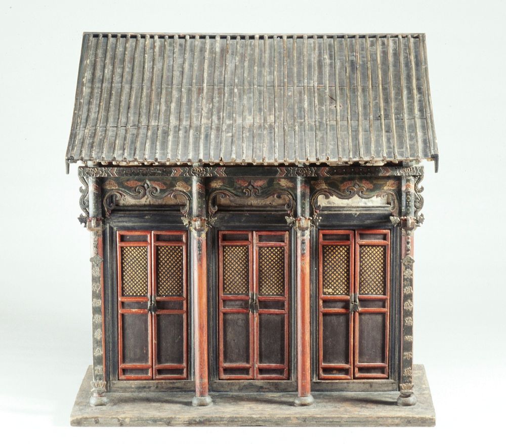 Model of a building with a sloping, ribbed roof, 4 columns on a small porch and 3 pairs of removable functional doors.…