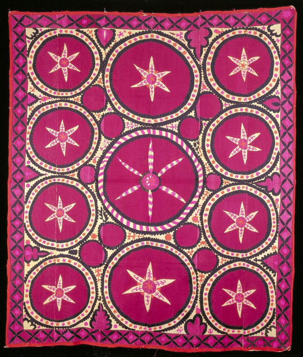 cream, magenta, black, orange and pink embroidery on natural cotton ground; red cotton binding around edge. Original from…
