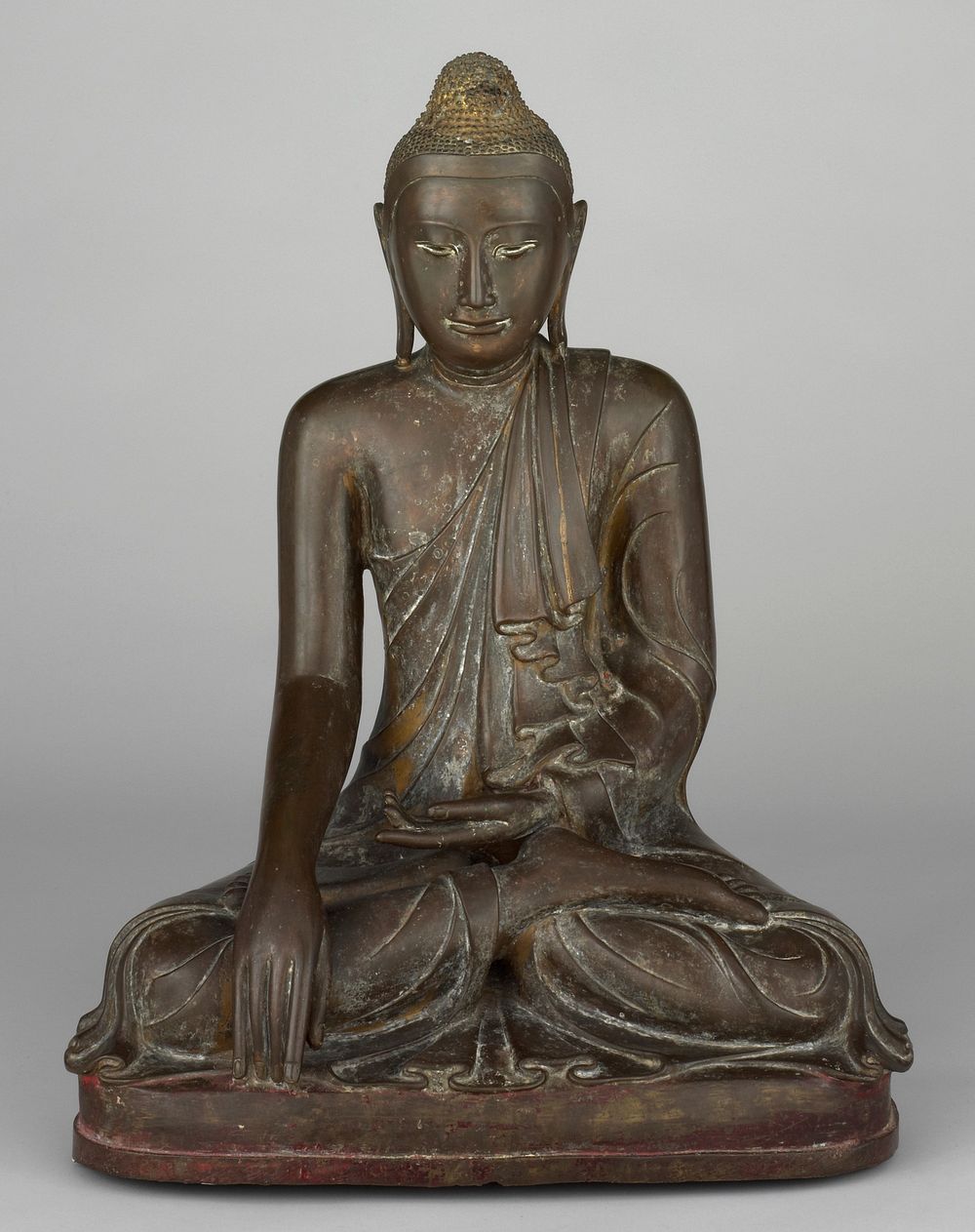 Mandalay style; Buddha seated in the bhumisparsamudra pose, his left hand is held in his lap and his right hand touches the…