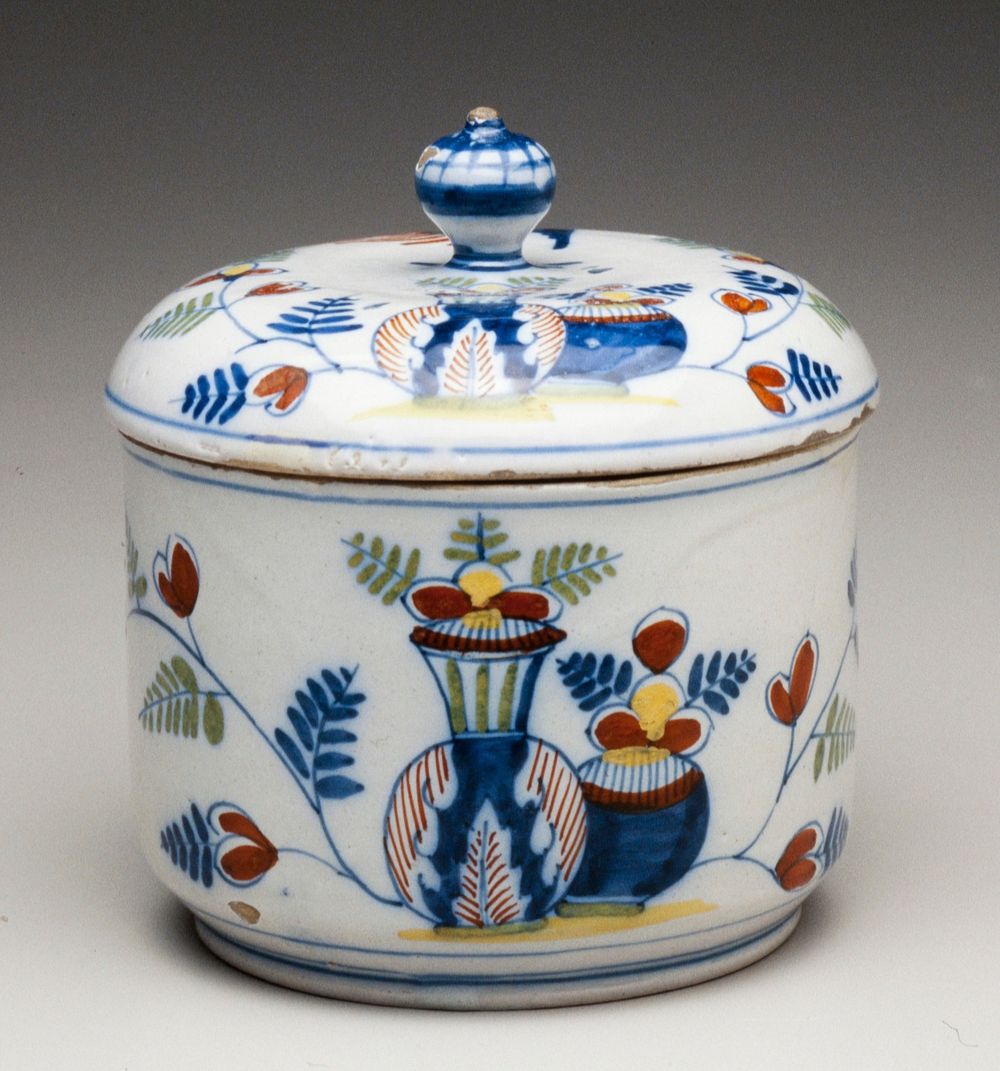 ceramic covered sugar pot; blue and white with addition of green, yellow and red; design of two vases with flowers opposed…